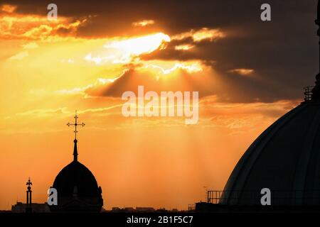Cross on a church dome in morning light through clouds; a silhouette of the domes of Chiesa di Sant'Alessandro in Zebedia, Milan city Stock Photo