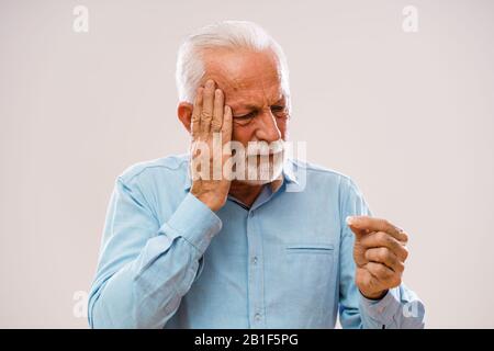 Portrait of senior man who is having headache. Stock Photo