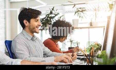 Young guy enjoying his job, working with colleagues in office Stock Photo