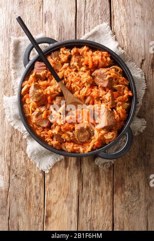Spicy cabbage with beef meat, tomatoes, carrots closeup in a pan on the table. Vertical top view from above Stock Photo