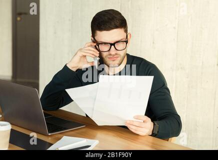 Displeased Office Manager Talking On Phone Holding Papers Sitting Indoor Stock Photo