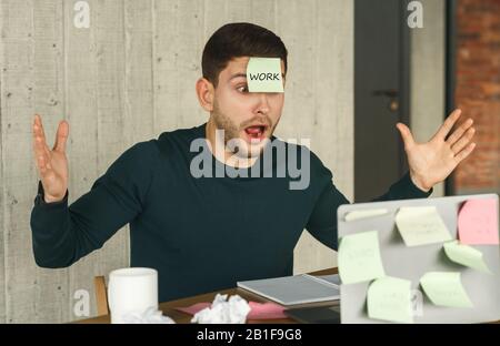 Guy Having Sticky Notes On Laptop And Face Sitting Indoor Stock Photo