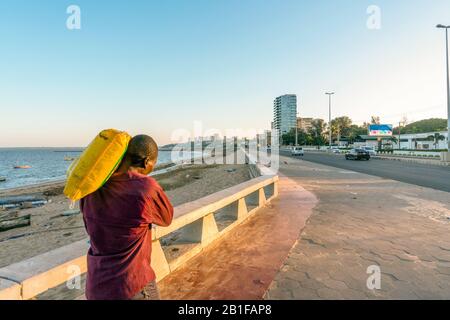 Maputo, Mozambique - May 13,2019: Man carrying heavy bag on his arm on  Costa do Sol Stock Photo