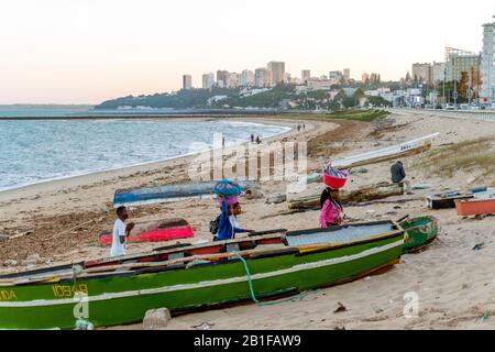 Maputo, Mozambique - May 13, 2019: Women carrying load and fish on their heads among fishermen's boats in Costa do Sol Stock Photo