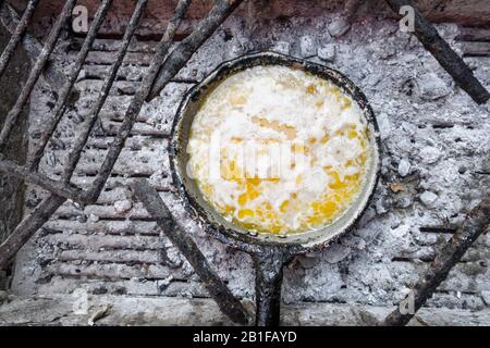 Clarifying butter on the frying pan on charcoal in Mozambique, Africa Stock Photo