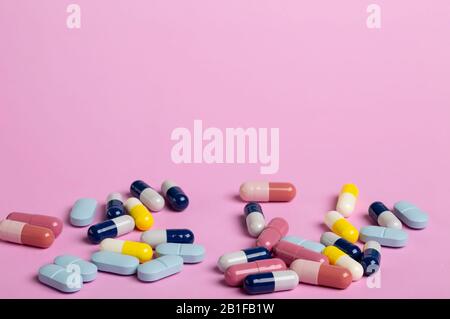 colourful medicine capsules and coloured pills on a pink background Stock Photo