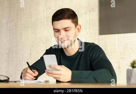 Student Guy Using Smartphone Learning Sitting At Home Stock Photo