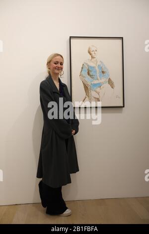Scarlett Clark as she poses next to her portrait, as part of an exhibition, David Hockney: Drawing from Life, which runs from 27 February to 29 June at the National Portrait Gallery in London. Stock Photo