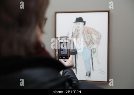 An art enthusiast viewing the exhibition takes a picture of David Hockney's 'Bruno Mars' portrait, as part of an exhibition, David Hockney: Drawing from Life, which runs from 27 February to 29 June at the National Portrait Gallery in London. Stock Photo