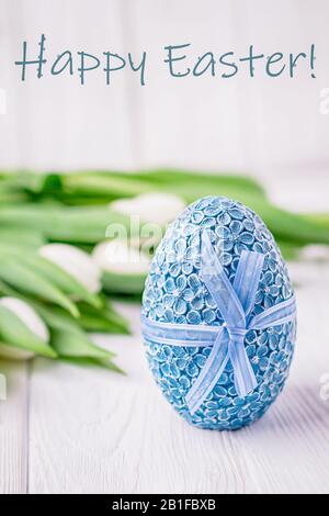 Happy Easter card. Blue Easter egg and delicate tulips on a white background Stock Photo