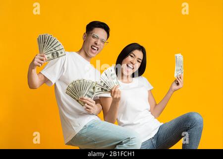 Super happy asian couple holding bunch of money Stock Photo