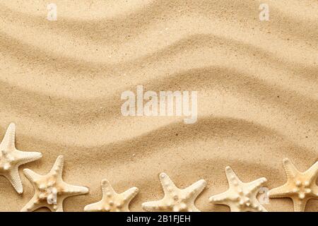 Starfishes on wavy sand background for summer designs. Top view, flat lay Stock Photo