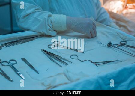 closeup, the hands of a nurses hand, an assistant surgeon takes a surgical instrument from a sterile table. In a sterile operating room. Removing a ma Stock Photo
