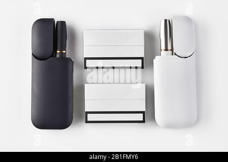 New generation black and white electronic cigarettes in open batteries and  two packs isolated on white. Hi-tech heating tobacco system. Tools used to  Stock Photo