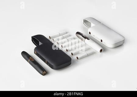 New generation, black and white, two electronic cigarettes and two open batteries, seven heatsticks isolated on white. New alternative technology. Hea Stock Photo