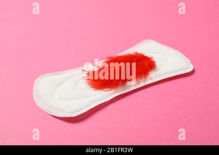Sanitary pad with red feather on pink background, close up Stock Photo