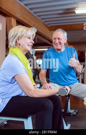 Senior woman in the gym exercising with dumbbells for fitness Stock Photo