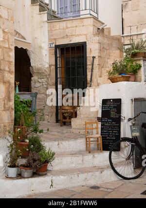 Plants, wooden chairs and a chalk board menu outside a restaurant in Cisternino, Val d’Istria, Puglia, Italy, Europe Stock Photo