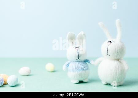 Easter concept. Two knitted bunnies staying near eggs laying on ground Stock Photo