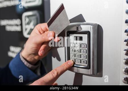 Man scanning security key card on electric lock and entering security system code to entry private building. Stock Photo