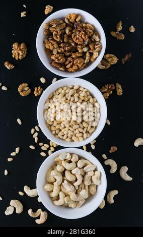 superfood concept, cedar, walnuts, cashew nuts in a plate on a black background Stock Photo