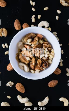 superfood concept, almond, cedar, walnuts, cashew nuts in a plate on a black background Stock Photo