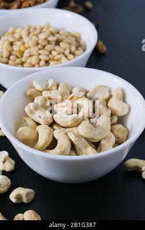 superfood concept, cedar, walnuts, cashew nuts in a plate on a black background Stock Photo