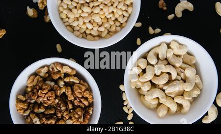 superfood concept, cedar, walnuts, cashew nuts in a plate on a black background Stock Photo