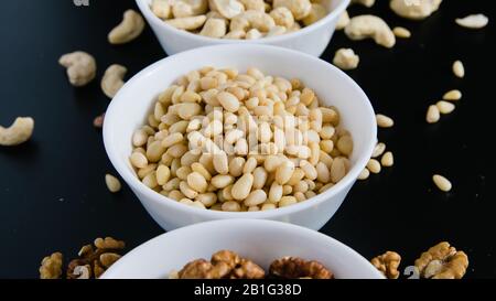 superfood concept, cedar, walnuts, cashew nuts in a plate on a black background Stock Photo