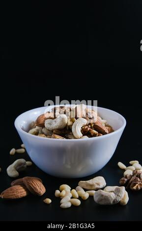 superfood concept, almond, cedar, walnuts, cashew nuts in a plate on a black background Stock Photo