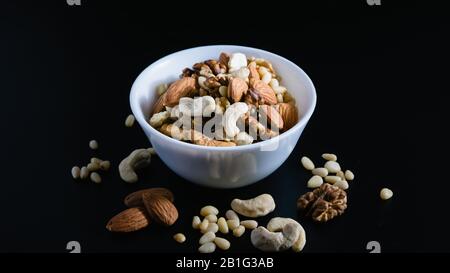 superfood concept, almond, cedar, walnuts, cashew nuts in a plate on a black background Stock Photo