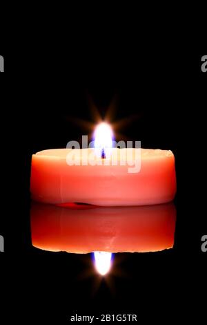 One pink tea light candle isolated on black glass with reflection Stock Photo