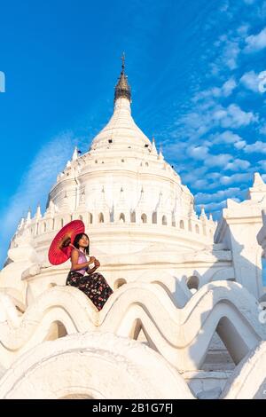 Beautiful young Burmese woman holding red umbrella at Hsinbyume Pagoda, Mingun, Mandalay Region, Myanmar Stock Photo