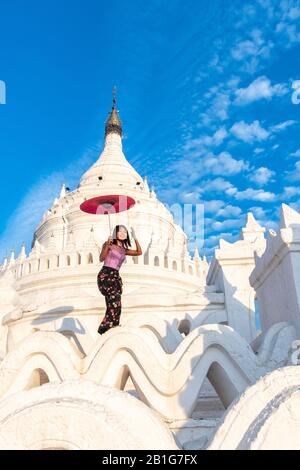 Beautiful young Burmese woman holding red umbrella at Hsinbyume Pagoda, Mingun, Mandalay Region, Myanmar Stock Photo