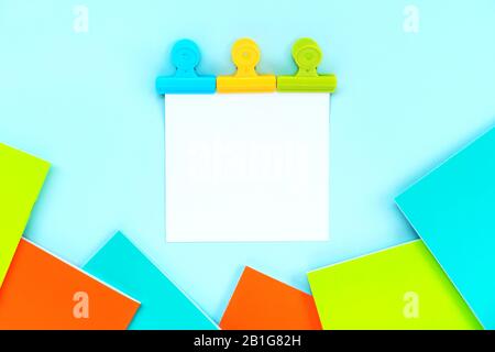 A white sheet for writing attached by three multi-colored stationery clips  Stock Photo