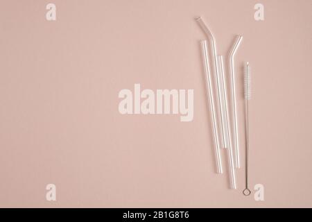 Reusable glass drinking straws with cleaning brush on brown background. Flat lay, top view. Zero waste, plastic free concept. Sustainable lifestyle. Stock Photo