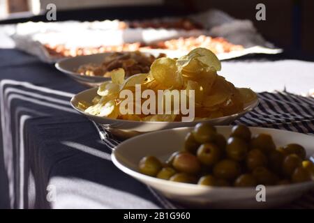 Spanish appetizer aperitif with crisps, olives and cookies among other things in a table in black Stock Photo