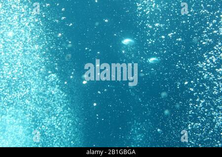 Blue ocean waves from underwater with bubbles. Light rays shining through. Great for backgrounds. Stock Photo