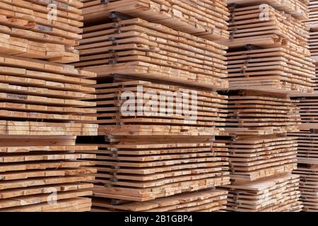 large stacks of wooden planks full frame background with selective focus and linear perspective Stock Photo