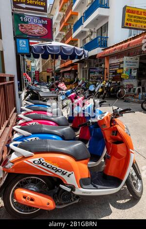 a long line of parked mopeds for hire at a motorcycles store or garage in patong on the thai island of phuket in thailand. Stock Photo