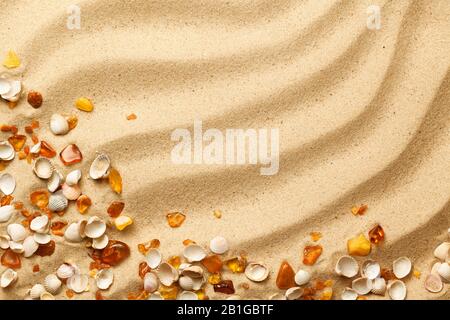 Ambers and seashells on sand background. Flat lay. Top view Stock Photo