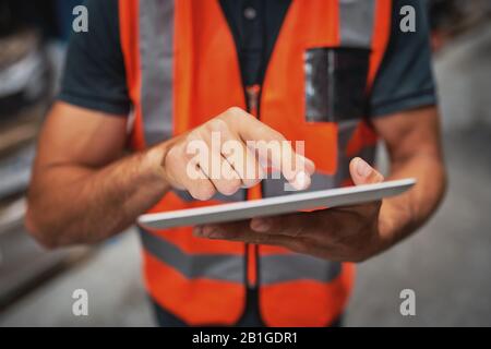 Close-up of man hands using digital tablet computer while standing in the warehouse Stock Photo