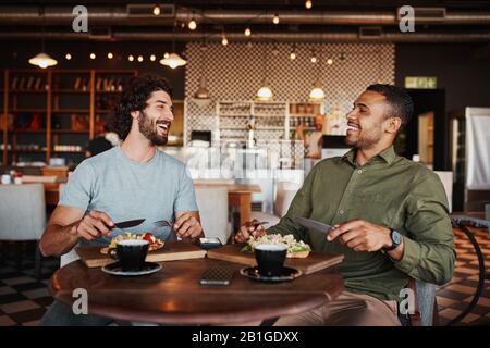 Friends enjoying italian brischetta food in cafe with coffee while laughing during conversation Stock Photo