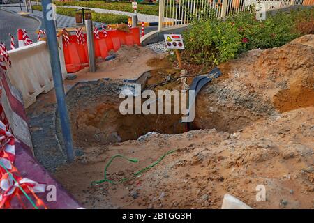 deep excavation with caution posts side of a road, part of construction work Stock Photo