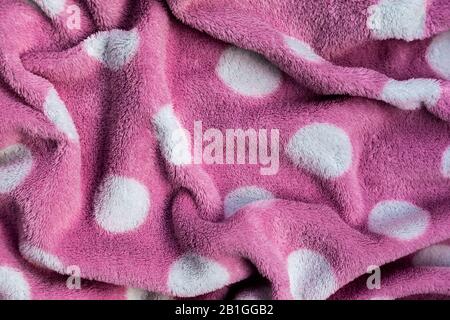 Pink delicate soft background of fur plush smooth fabric with white circles. Texture of light red soft fleecy blanket textile. Stock Photo