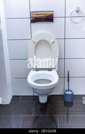 Toilet room with open wall-hung toilet bowl. Stock Photo