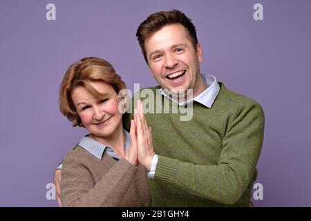 Mature woman and young man mother and son giving each other a high five. Teamwork concept, studio shot Stock Photo