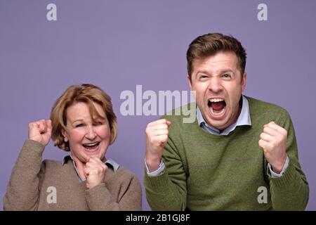 Happy overjoyed family mother and son clenching fists and opening mouths widely in excitement, rejoicing at success, positive news or achievement. Joy Stock Photo