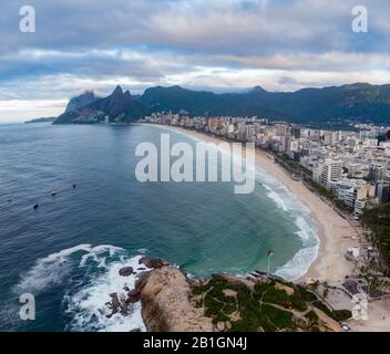 Arpoador rock in Rio de Janeiro with Ipanema beach in the foreground and wider cityscape including Two Brothers mountain in the background