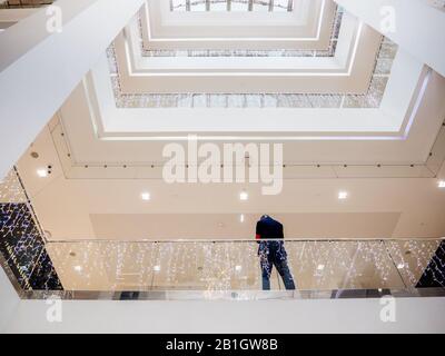 Surveillance during winter holidays in France - Low angle view of black ethnicity guard security male in tall shopping mall center Stock Photo